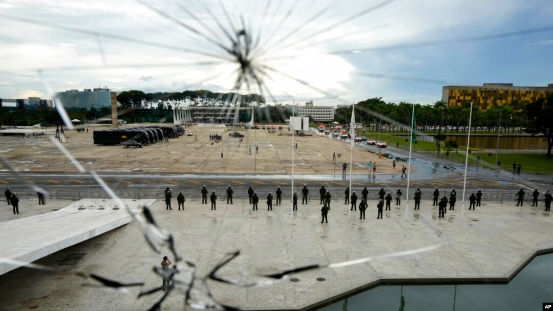 A strong security presence is set up at the Esplanade of Ministries, as seen through a window damaged when supporters of former President Jair Bolsonaro stormed the area on Sunday, at the Planalto Palace in Brasilia, Brazil, Jan. 11, 2023.