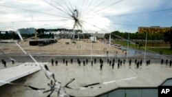 A strong security presence is set up at the Esplanade of Ministries, as seen through a window damaged when supporters of former President Jair Bolsonaro stormed the area on Sunday, at the Planalto Palace in Brasilia, Brazil, Jan. 11, 2023.