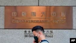 Seorang pria berjalan melewati pintu masuk kantor pusat perusahaan properti China Evergrande Group di Hong Kong, 4 Oktober 2021. (Foto: Vincent Yu/AP Photo)