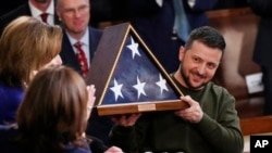 FILE: Ukrainian President Volodymyr Zelenskyy holds an American flag that was gifted to him by House Speaker Nancy Pelosi of Calif., after he addressed a joint meeting of Congress on Capitol Hill in Washington, Dec. 21, 2022. 