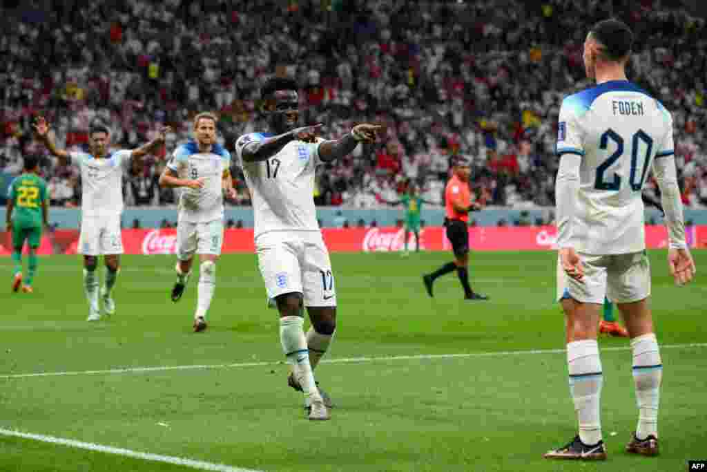 Attaquant ya Angleterre #17 Bukayo Sak (C) a azali kosepela mongete na ye na match na Sénégal na 8e ya Mondial Qatar 2022 na stade Al-Bayt, Doha, 4 décembre 2022. (Photo by Paul ELLIS / AFP)