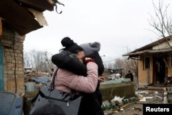 A local resident embraces a friend at a house damaged during a Russian missile strike, in Kyiv, Ukraine, Dec. 29, 2022.
