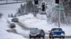 Mobil perlahan-lahan berjalan melalui persimpangan jalan di di Duluth, Minnesota utara, Kamis, 15 Desember 2022. (AP Photo/Holden Law)