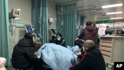 中国河北廊坊第四人民医院急诊室内病人家属聚在病人床前。（2022年12月22日）