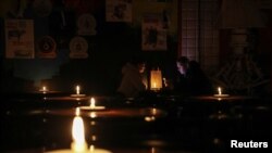 People sit in a pub lit with candles during a power outage after critical civil infrastructure was hit by Russian missile attacks, as Russia's invasion of Ukraine continues, in Lviv, Ukraine Nov. 24, 2022.
