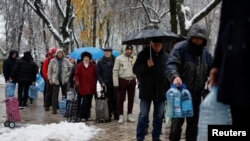 FILE - Local residents stand in line to fill up bottles with fresh drinking water after critical civil infrastructure was hit by Russian missile attacks in Kyiv, Nov. 24, 2022. 