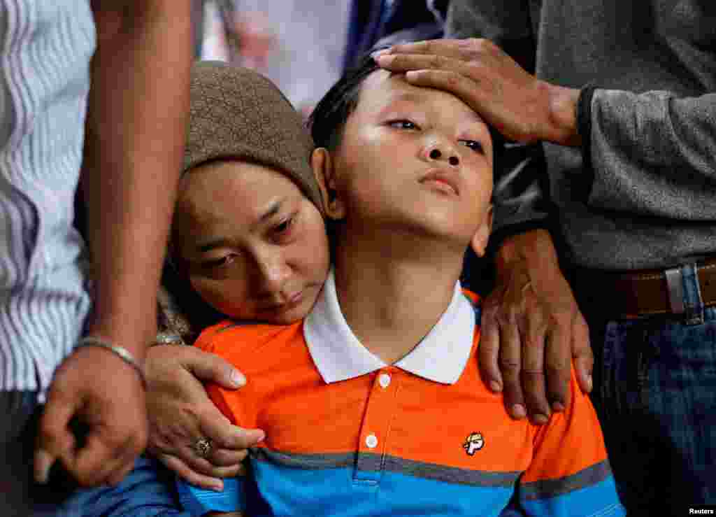 Siti Sarah and Al Fikri Ibnu Sofyan, wife and the third son of Agus Sofyan, a police officer who was killed in a blast at a district police station, mourn during the funeral in Bandung, West Java province, Indonesia.
