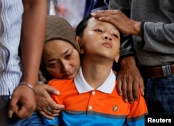 Siti Sarah dan Al Fikri Ibnu Sofyan, istri dan anak ketiga Agus Sofyan, polisi yang tewas dalam ledakan di Polres, berduka saat pemakaman di Bandung, Jawa Barat, 7 Desember 2022. (Foto : REUTERS/Willy Kurniawan)