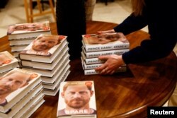 Seorang penjaga toko buku Waterstones, di London, Inggris, menata 'Spare' - buku memoar Pangeran Harry - yang secara resmi mulai dijual di toko itu, 10 Januari 2023. (REUTERS/Peter Nicholls)