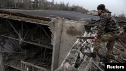 A Ukrainian soldier stands on the roof of a university damaged in a recent missile attack, in Kramatorsk Ukraine, Dec. 13, 2022. 