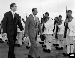FILE - In this March 25, 1965 file photo, King Constantine II of Greece, left, and Prince Philip of Britain review an honor guard of the Greek Royal Evzones Guard during the prince's visit to Greece.