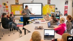 FILE - In this photo taken Feb. 12, 2015, sixth grade teacher Carrie Young guides her students through an exercise on their laptops. (AP Photo/Ty Wright) 
