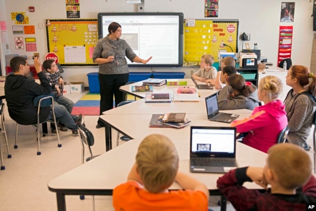 ComIn this photo taken Feb. 12, 2015, sixth grade teacher Carrie Young guides her students through an exercise on their laptops. (AP Photo/Ty Wright)