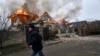 Un residente local pasa corriendo frente a una casa en llamas alcanzada por los bombardeos rusos en Kherson, Ucrania, en la víspera de Navidad ortodoxa el viernes 6 de enero de 2023. (Foto AP/LIBKOS)