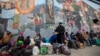 Migrantes comen y esperan ayuda, acampados en una calle del centro de El Paso, Texas, el 18 de diciembre de 2022.