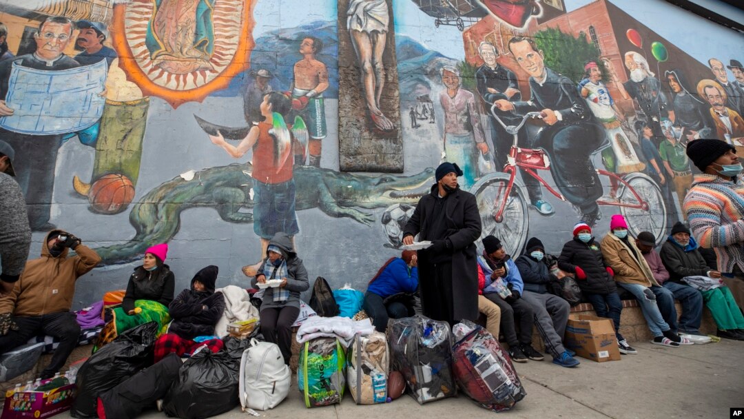 Migrantes comen y esperan ayuda, acampados en una calle del centro de El Paso, Texas, el 18 de diciembre de 2022.