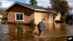 Nick Enero wades through floodwaters while helping his brother salvage items from his Merced, Calif., home as storms continue battering the state on Jan. 10, 2023. (AP Photo/Noah Berger)