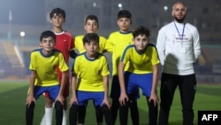 Children wearing uniforms like those of the Ecuador national football team pose before "Camps World Cup" starts at the Idlib Municipal Stadium in the rebel-held northwestern Syrian city on Nov. 19, 2022. Organizers hope the soccer match spotlights communities battered by war.