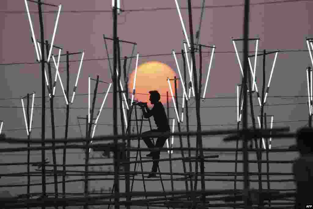A worker installs lights at an outdoor location of a film shoot in Bhopal, India.