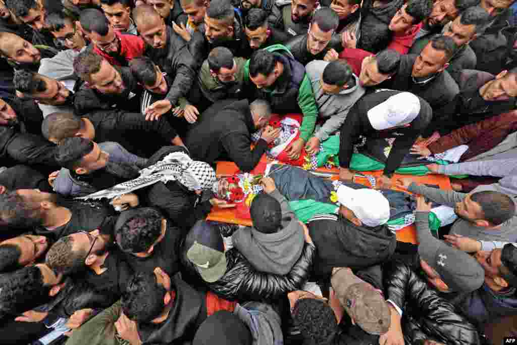 Ожалостените се собираат околу телата на Палестинците убиени за време на судирите со израелските армиски сили, пред мртовечница во градот Рамала на окупираниот Западен Брег.