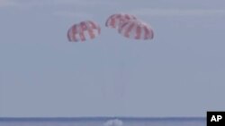 This photo provided by NASA shows the Orion capsule coming back from the moon. The capsule made a blisteringly fast return Sunday, Dec. 11, 2022, parachuting into the Pacific off Mexico. (NASA via AP)