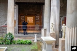 A woman takes pictures of the "triclinium", or dining room, called Hall of Pentheus, part of the Ancient Roman Domus Vettiorum, House of Vettii (AP Photo/Andrew Medichini)