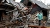 A woman stands near debris of her house following Russian shelling, in Kurakhove, Donetsk region, Ukraine, Dec. 8, 2022.