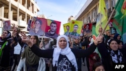 Syrian-Kurdish demonstrators raise pictures of people killed during conflict, as they protest against Turkey's threats against their region, in the northeastern Syrian Kurdish-majority city of Qamishli, on Nov. 27, 2022.