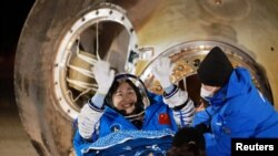 Astronaut Liu Yang melambaikan tangannya sesaat setelah ia keluar dari kapsul pesawat ruang angkasa Shenzou-14 yang mendarat di stasiun pendaratan Dongfeng, China, pada 4 Desember 2022. (Foto: China Daily via Reuters)