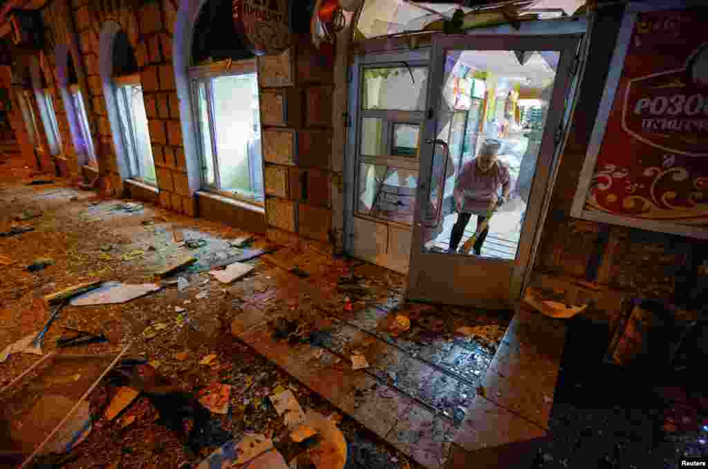 An employee of a grocery store removes debris in a residential building damaged in shelling in the course of Russia-Ukraine conflict in Donetsk, Russian-controlled Ukraine.