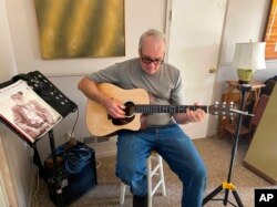 Bob Dorobis plays his guitar at home in Middletown, N.J., on Dec. 4, 2022. Dorobis redoubled his efforts to learn fingerpicking during the pandemic. (Jeanann Dorobis via AP)