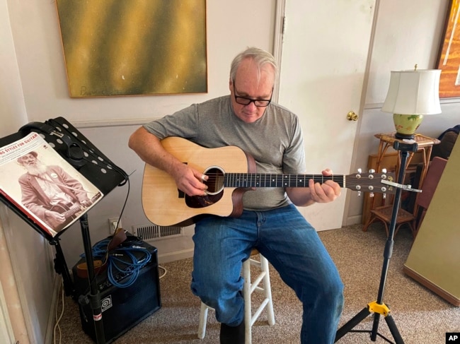 Bob Dorobis plays his guitar at home in Middletown, N.J., on Dec. 4, 2022. Dorobis redoubled his efforts to learn fingerpicking during the pandemic. (Jeanann Dorobis via AP)