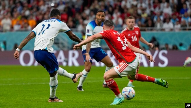 England's Marcus Rashford, left, scores past Wales' Connor Roberts for his side's third goal during the World Cup group B soccer match at Ahmad Bin Ali Stadium in Al Rayyan, Qatar, Nov. 29, 2022.