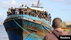 FILE - Migrants stand onboard a fishing boat at the port of Paleochora, following a rescue operation off the island of Crete, Greece, Nov. 22, 2022.