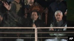 Pakistan's former Prime Minister and opposition leader Imran Khan, center in seated, addresses to his supporters during a rally, in Rawalpindi, Pakistan, Nov. 26, 2022. 