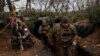 Ukrainian servicemen walk past a decorated Christmas tree in the trenches on the front line on Christmas Eve in Bakhmut, Dec. 24, 2022. 