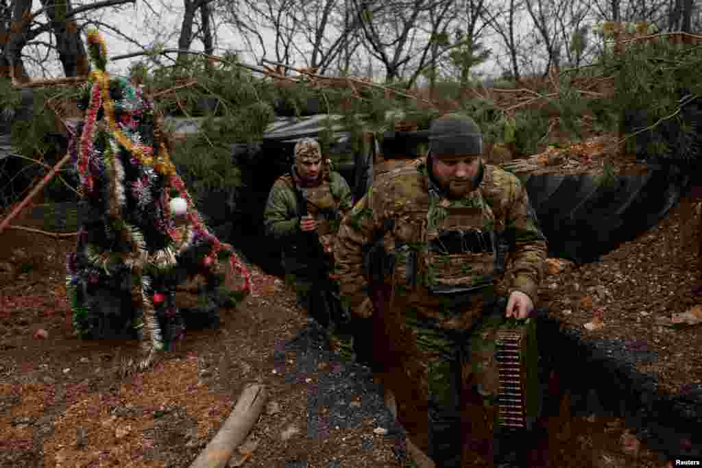 Ukrainian servicemen walk past a decorated Christmas tree in the trenches on the front line on Christmas Eve in Bakhmut.