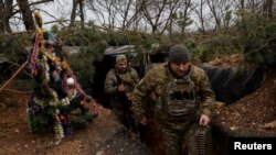Ukrainian servicemen walk past a decorated Christmas tree in the trenches on the front line on Christmas Eve in Bakhmut, Dec. 24, 2022. 