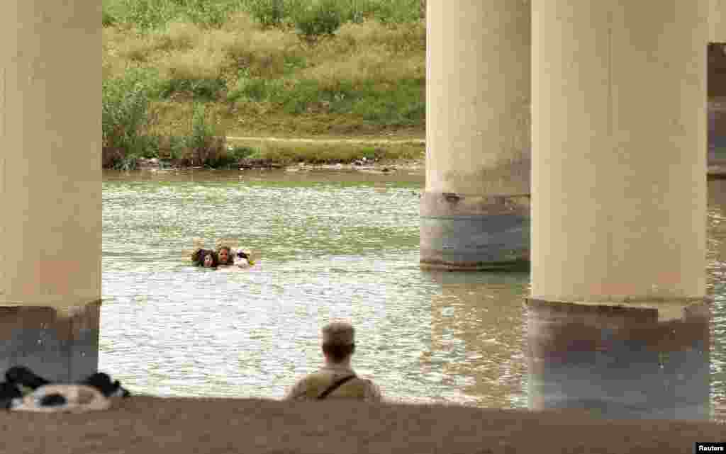 Migrants swim across the Rio Grande&nbsp;in Eagle Pass, Texas, Dec. 18, 2022, as U.S. border cities prepare for an increase of asylum seekers when COVID-era Title 42 migration restrictions are set to end.