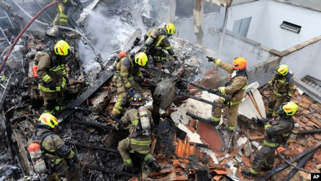 Bomberos trabajan en el lugar del accidente de una avioneta que cayó sobre casas en una zona residencial de Medellín, Colombia, el lunes 21 de noviembre de 2022. El avión se estrelló poco después de despegar del aeropuerto Olaya Herrera de Medellín. (Foto AP/Jaime Saldarriaga)