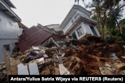 Warga menyelamatkan barang-barang di reruntuhan rumah yang rusak parah pascagempa Cianjur, Jawa Barat, Senin, 23 November 2022. (Foto: Antara/Yulius Satria Wijaya via REUTERS)
