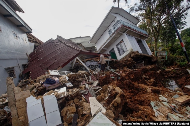 Warga menyelamatkan barang-barang di reruntuhan rumah yang rusak parah pascagempa Cianjur, Jawa Barat, Senin, 23 November 2022. (Foto: Antara/Yulius Satria Wijaya via REUTERS)