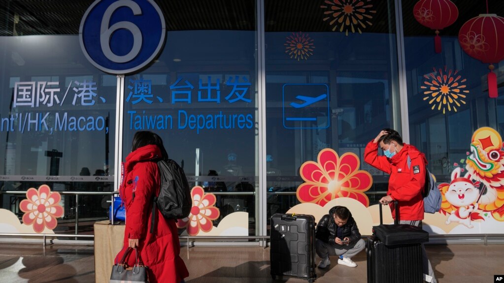 旅客戴着口罩拖着行李来到北京首都机场国际航班出发航站楼入口（2022年12月29日）(photo:VOA)