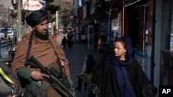 Seorang perempuan tampak menatap anggota pasukan Taliban ketika berjalan di salah satu area di Kabul, pada 26 Desember 2022. (Foto: AP/Ebrahim Noroozi)