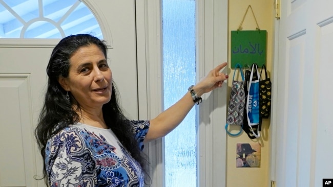 FILE -- Koloud "Kay" Tarapolsi points to a mask holder made by her daughter that has the phrase "To Your Health" written in Arabic on it, at her home in Redmond, Washington.