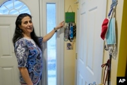 FILE -- Koloud "Kay" Tarapolsi points to a mask holder made by her daughter that has the phrase "To Your Health" written in Arabic on it, at her home in Redmond, Washington. (AP Photo/Ted S. Warren)