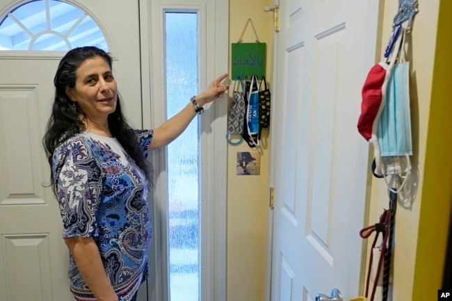 FILE -- Koloud "Kay" Tarapolsi points to a mask holder made by her daughter that has the phrase "To Your Health" written in Arabic on it, at her home in Redmond, Washington. (AP Photo/Ted S. Warren)