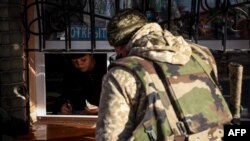 A Ukrainian soldier buys food at a kiosk in Kostyantynivka, eastern Ukraine, Dec. 1, 2022. Every morning begins with a familiar scene: soldiers filling up trucks, sipping steaming coffee and catching up between bites of fresh hot dogs.