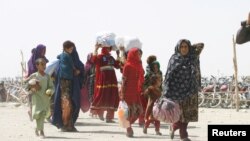 FILE - People from Afghanistan walk with their belongings as they cross into Pakistan at the 'Friendship Gate' crossing point, in the Pakistan-Afghanistan border town of Chaman, Pakistan, Sept. 7, 2021. 