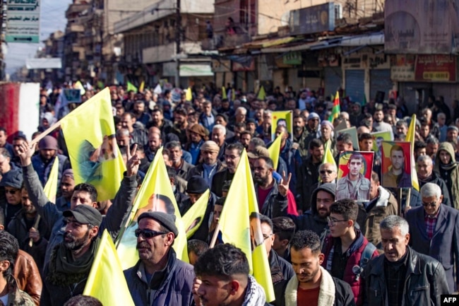 Syrian-Kurdisg demonstrators raise flags bearing an image of jailed leader Abdullah Ochalan, as they protest against Turkey's threats against their region, in the northeastern Syrian Kurdish-majority city of Qamishli, on Nov. 27, 2022. -
